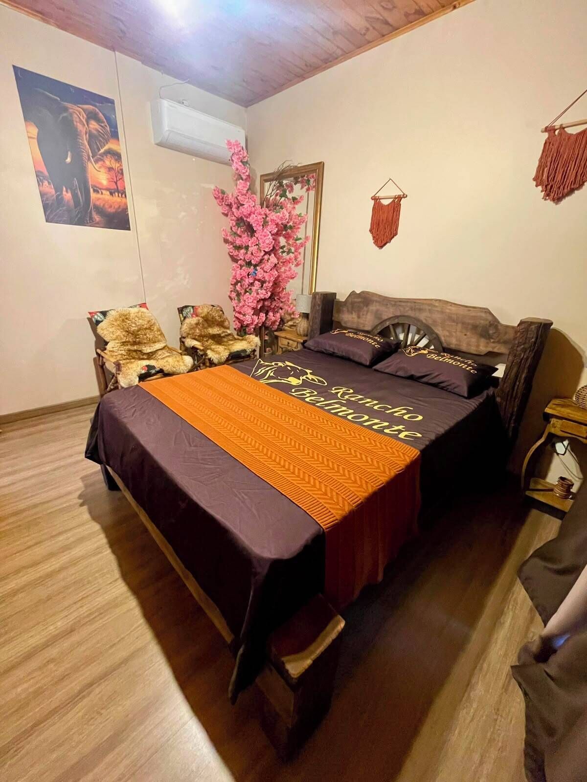A bedroom with a bed, a chair, a mirror, and a wall-mounted air conditioner.
