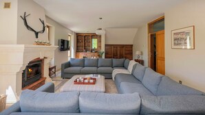 A living room with a fireplace, a sectional sofa, and a wooden cabinet.