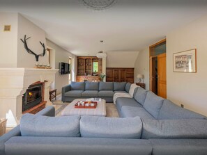 A living room with a fireplace, a sectional sofa, and a wooden cabinet.