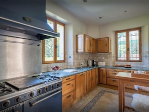 A kitchen with a large stove, wooden cabinets, a window, and a tiled backsplash.