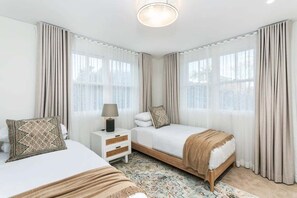 A hotel room with two beds, a nightstand, a lamp, and a patterned rug. - FITZ2 - Kirribilli Comfort | 2-Bed Apartment With Harbour Views (Kirribilli)