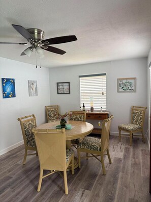 A dining room with a round table, four chairs, a ceiling fan, and wall art. - St. Pete Getaway - Spacious 4-bedroom house (St. Petersburg)