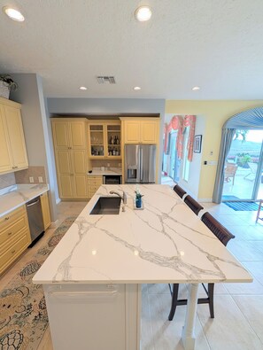 A modern kitchen with a central island, built-in appliances, and a view to an outdoor patio. -  Pristine 6 bed 6 bath villa in the islands premier gated community!!! (Christiansted)