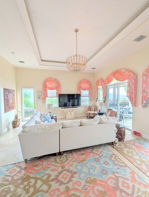A spacious living room with a large sofa, a television, and a patterned rug. -  Pristine 6 bed 6 bath villa in the islands premier gated community!!! (Christiansted)