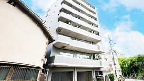Um edifício com vários andares, varandas, uma porta de garagem e céu claro.