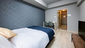 Quarto de hotel com cama, escrivaninha e televisão.