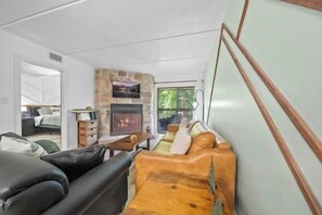 Ein modernes Wohnzimmer mit Kamin aus Stein, einer Ledersofa und einem Holztisch.