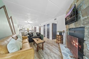 A spacious living area with a fireplace, a sofa set, and a kitchen in the background. - 2bd/2bth/3Pools/BearSightings (Gatlinburg)