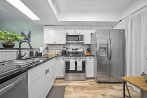 Eine moderne Küche mit Edelstahlgeräten, weißen Schränken und einer Holz Arbeitsplatte.