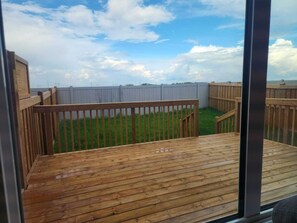 Un deck de madera con vista a un patio trasero cercado.