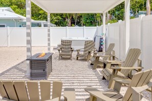 Um pátio ao ar livre com cadeiras Adirondack, lareira e banheira de hidromassagem.