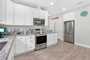 A modern kitchen with white cabinetry, stainless steel appliances, and a wooden floor. - Isla Ohana: Key Largo, Jacuzzi, Private Yard, Playset, BBQ (Key Largo)