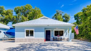A small, single-story building with a light blue exterior and a dark blue door. - Isla Ohana: Key Largo, Jacuzzi, Private Yard, Playset, BBQ (Key Largo)