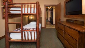 A bunk bed with a television on a wooden dresser, a hallway with a patterned carpet, and a door leading to another room. - Orlando | Family Treehouse Retreat | Pool + Spa (Lake Buena Vista)