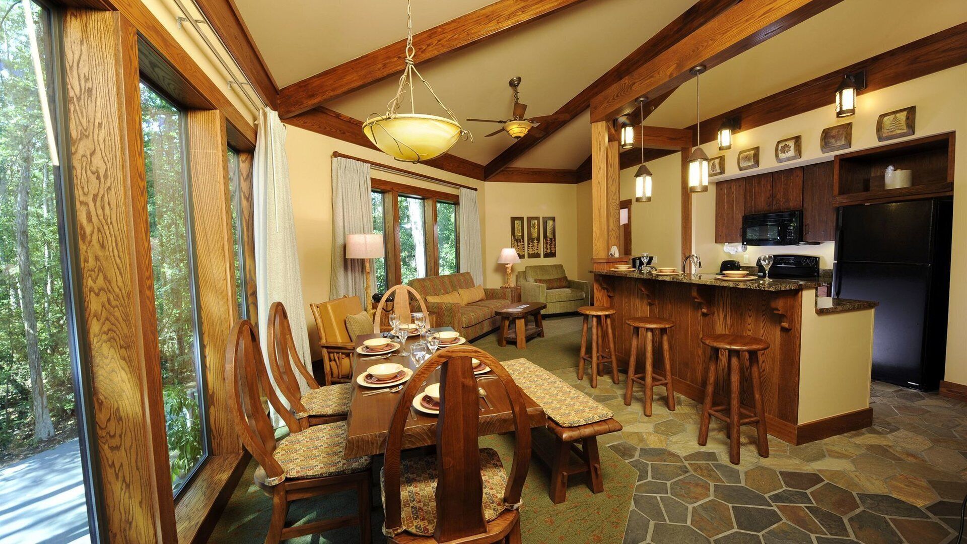 Un comedor amplio con techo alto y vigas de madera, una sala de estar acogedora con chimenea, y una cocina con salpicadero de piedra.