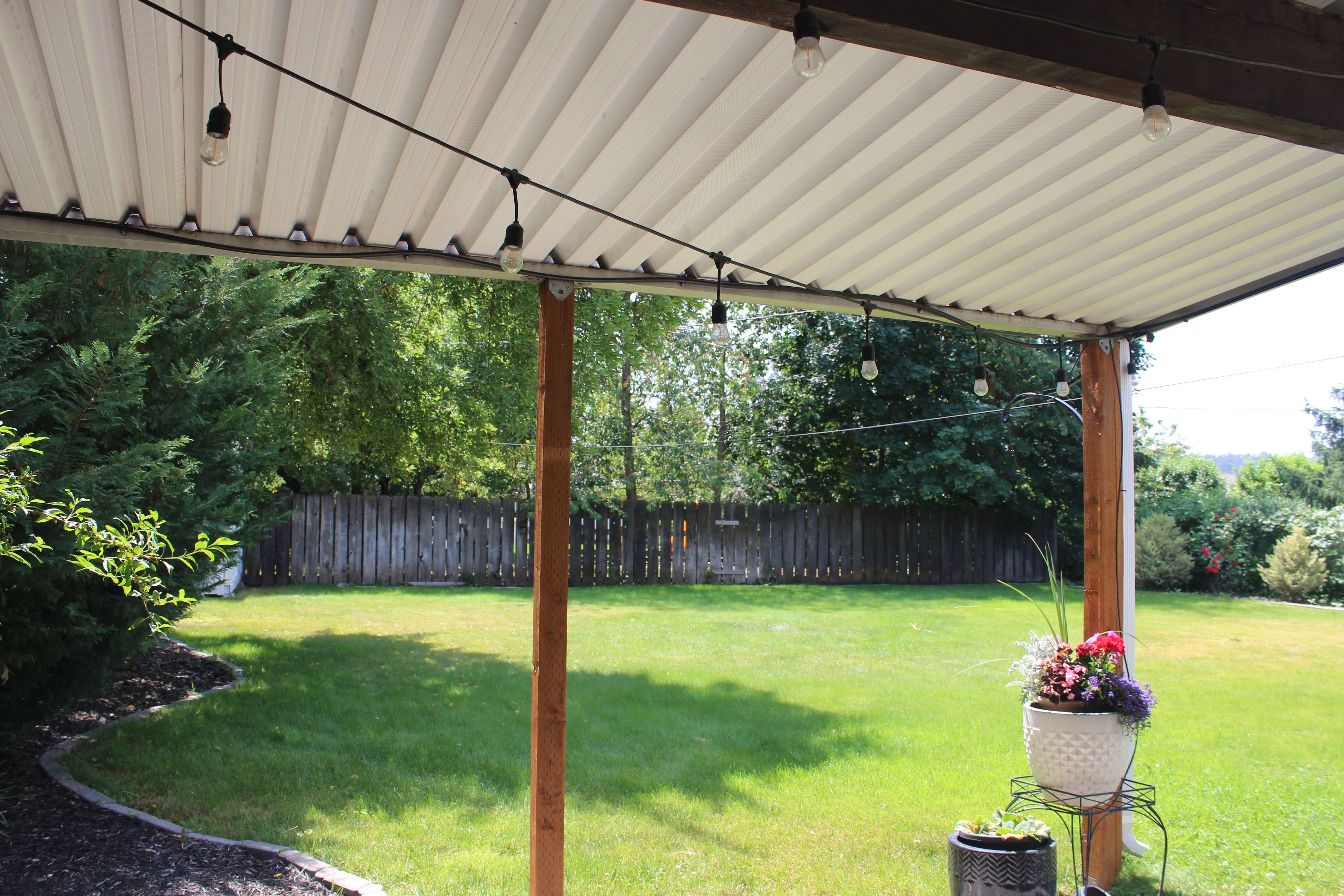 A covered patio area with a view of a backyard.
