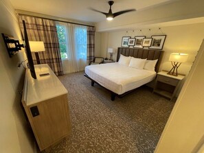 A hotel room with a bed, bedside tables, a desk, a ceiling fan, and a window with curtains. - Orlando | Large Family Retreat | Pool + Spa | 3BR Sleeps 12 (Lake Buena Vista)