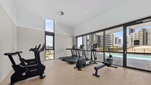 A gym with cardio machines, a rowing machine, and a bench. - 2 bed  2 bath Pool Car Park (Mermaid Beach)