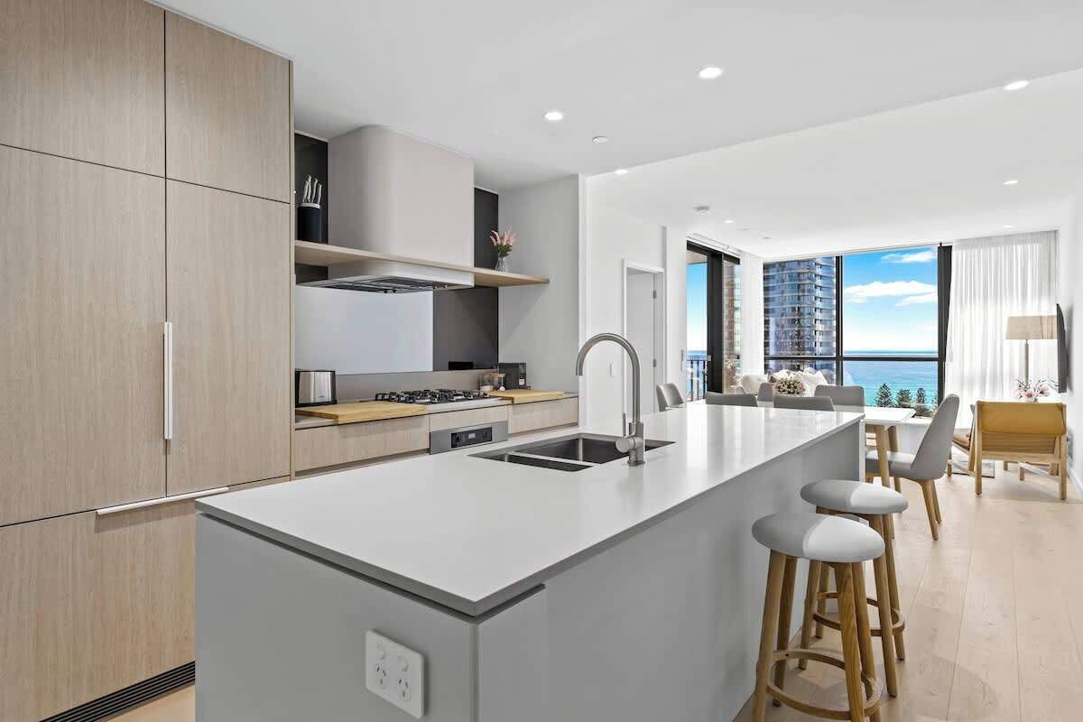 A modern kitchen with a central island, a dining area with a view, and a large window.