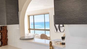 A kitchen with a view of the ocean, a white countertop, and a decorative animal figurine.