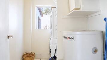 A laundry room with a white water heater, a washing machine, and a drying machine.