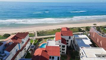 A coastal hotel with multiple buildings, a swimming pool, and a beach view.