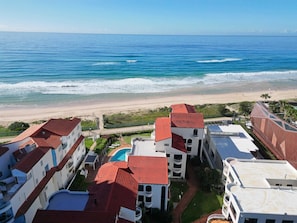 Ein Küstenhotel mit mehreren Gebäuden, einem Swimmingpool und Blick auf den Strand.