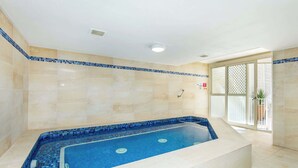 Ein Wellnessbereich mit einer großen Badewanne, gefliesten Wänden und einem Fenster mit Aussicht.