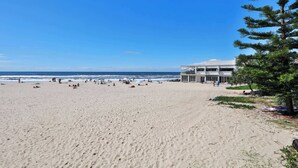 Ein Strand mit einem mehrstöckigen Gebäude und Balkonen.