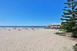 A beach with a building that has multiple floors and balconies. - 3BR Opposite Burleigh Beach  Pool  Car Park (Burleigh Heads)