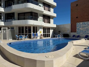 A swimming pool with lounge chairs and a building with multiple balconies. - 3BR Opposite Burleigh Beach  Pool  Car Park (Burleigh Heads)