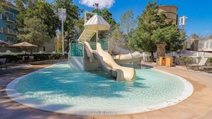 Un parc aquatique doté d’un toboggan central, d’une piscine et entouré d’arbres.