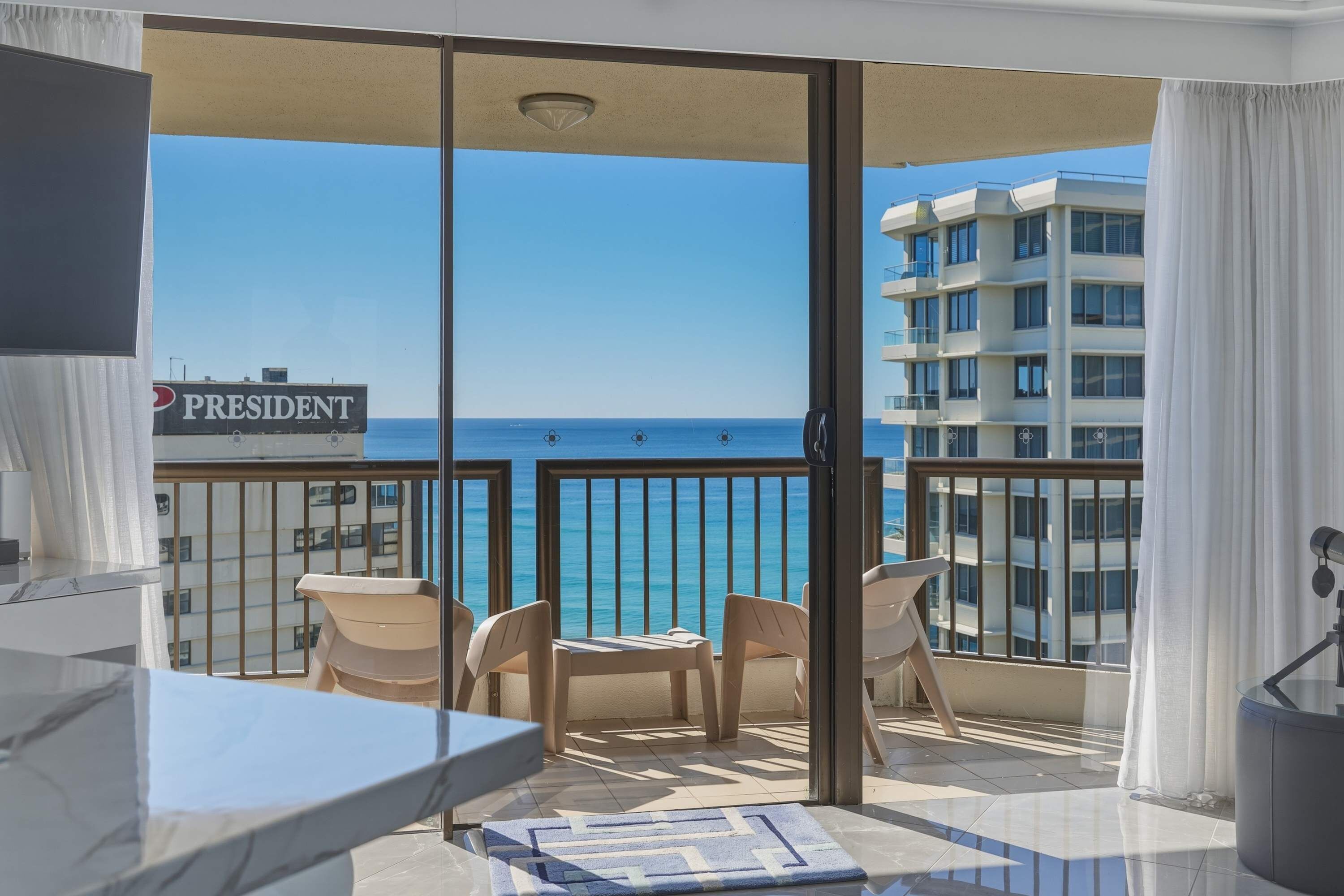 Ein Balkon mit Blick auf den Ozean, zwei Stühle, ein Tisch und ein Schild mit der Aufschrift 'PRESIDENT'.