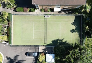 An aerial view of a tennis court surrounded by greenery and a parking area. - Lvl 15 Sunrise + Sunset Views | Pool + Parking (Surfers Paradise)
