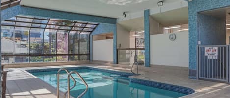 Una piscina interior con paredes de vidrio transparente, suelo de baldosas y un letrero que dice 'DRY OFF'.