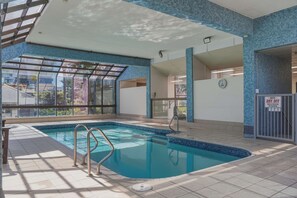 Una piscina interior con paredes de vidrio transparente, suelo de baldosas y un letrero que dice 'DRY OFF'.
