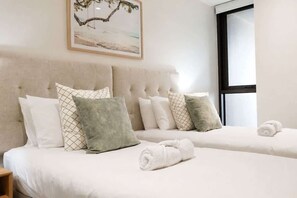 Ein Hotelzimmer mit zwei Betten, einem großen Fenster und einem Bild an der Wand.