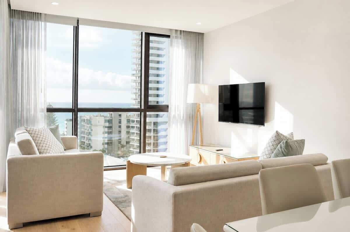 Un salon moderne avec un ensemble de canapés, une table basse et un téléviseur à écran plat fixé au mur.