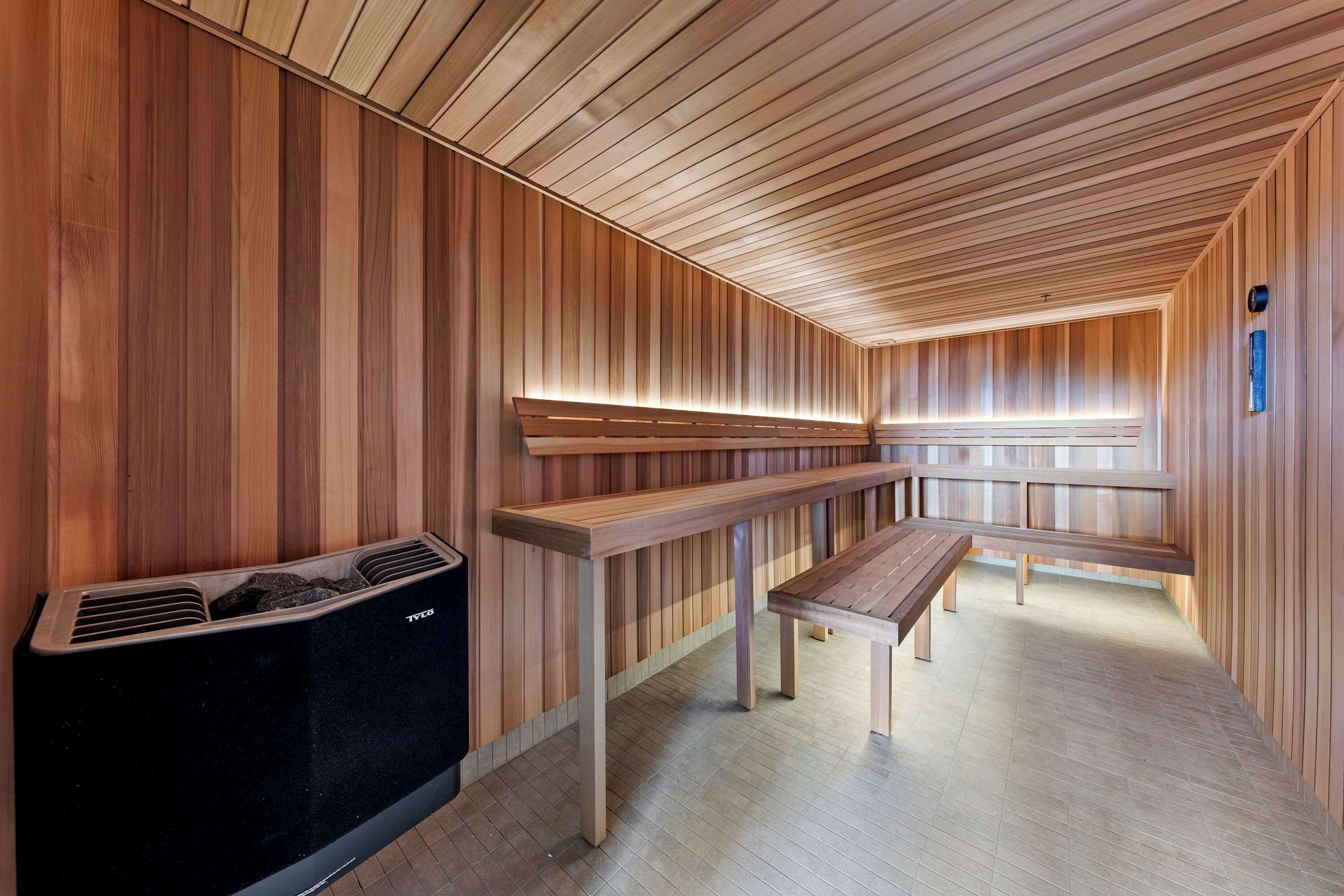 A sauna room with wooden walls, benches, and a heated floor.