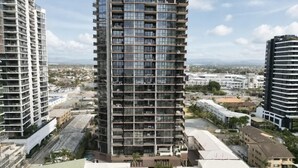 A high-rise building with multiple floors, large windows, and a modern architectural design. - 2BR Ocean Views Pool Gym Sauna (Mermaid Beach)