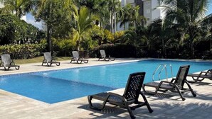 A swimming pool with lounge chairs and palm trees. - Spacious Condo With Pool, Gym, and Central AC in Santiago (Puñal)