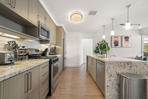 Una cocina moderna con electrodomésticos de acero inoxidable, armarios de madera y encimera de mármol.