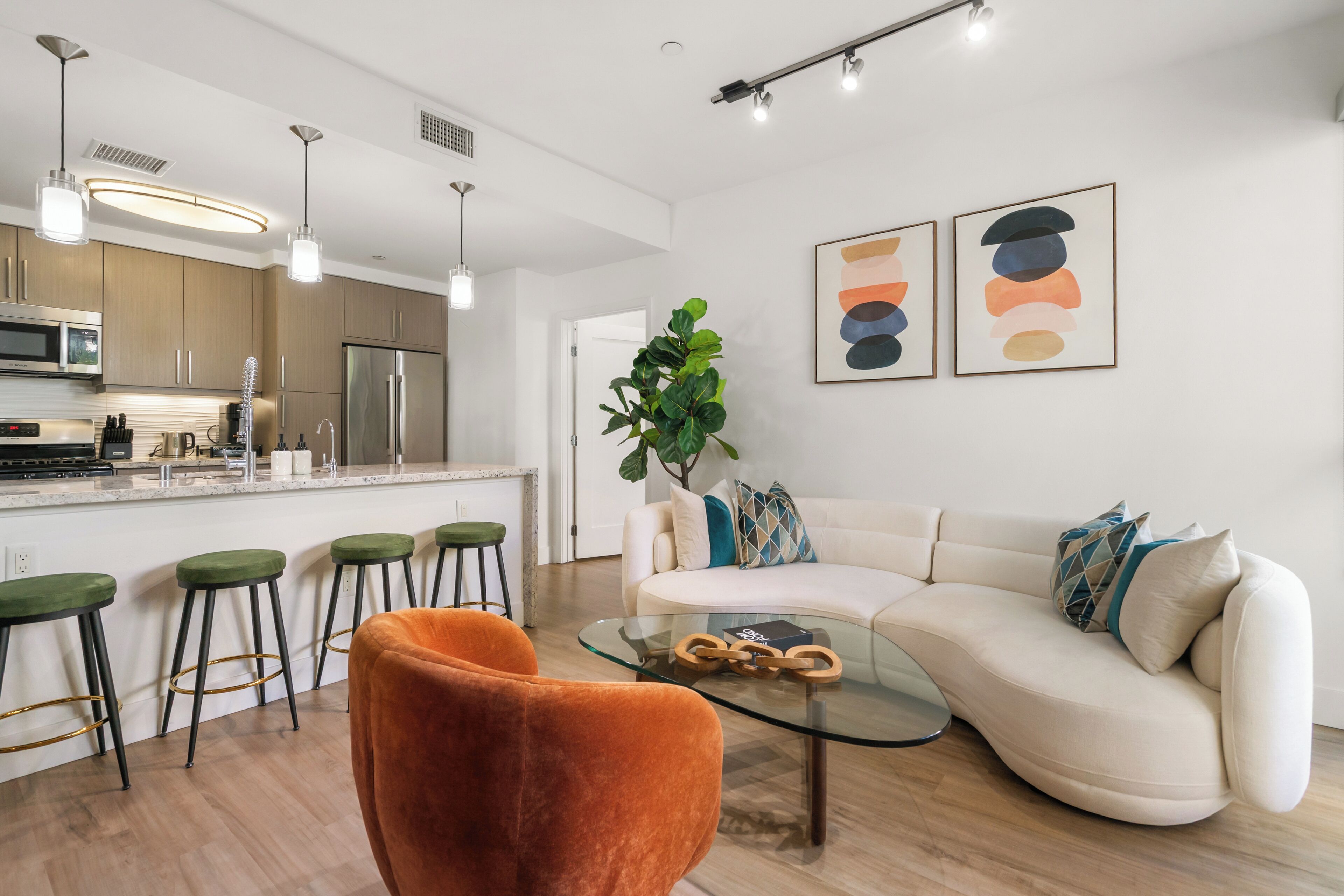 Un salon moderne avec une table basse en verre, un canapé et des tabourets de bar verts.
