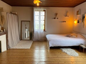 A bedroom with a wooden floor, a bed with white bedding, a window with curtains, and a mirror. - Domaine des Brunis - Large, charming home with a private pool (Nègrepelisse)