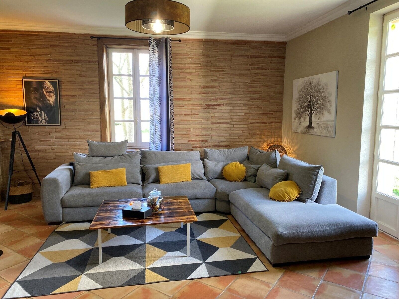 A modern living room with a grey sectional sofa, a coffee table, and a patterned rug.