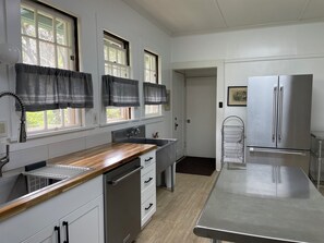 A kitchen with white cabinets, a stainless steel refrigerator, and a wooden countertop. - Historic 5-Bedroom Home in Upcountry Maui (Makawao)