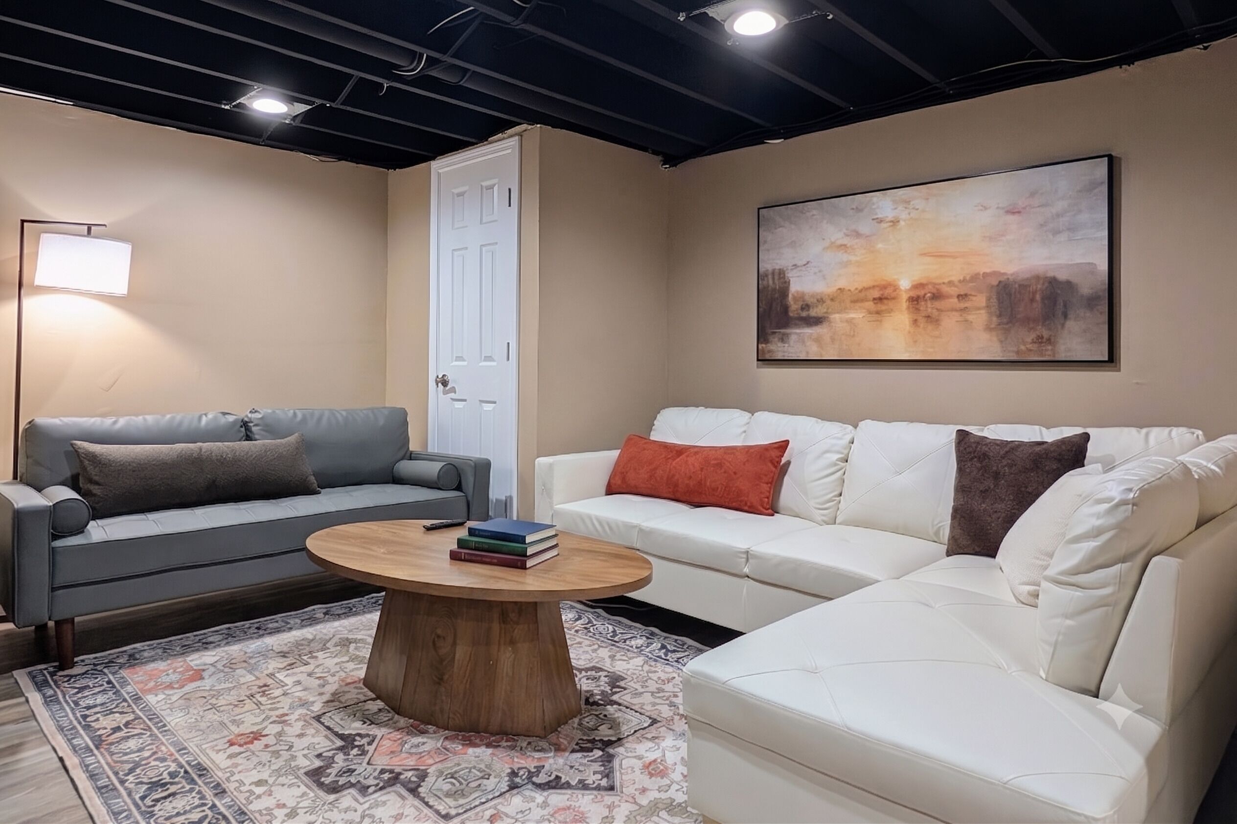 A living room with two sofas, a coffee table, a rug, a painting, and a door.