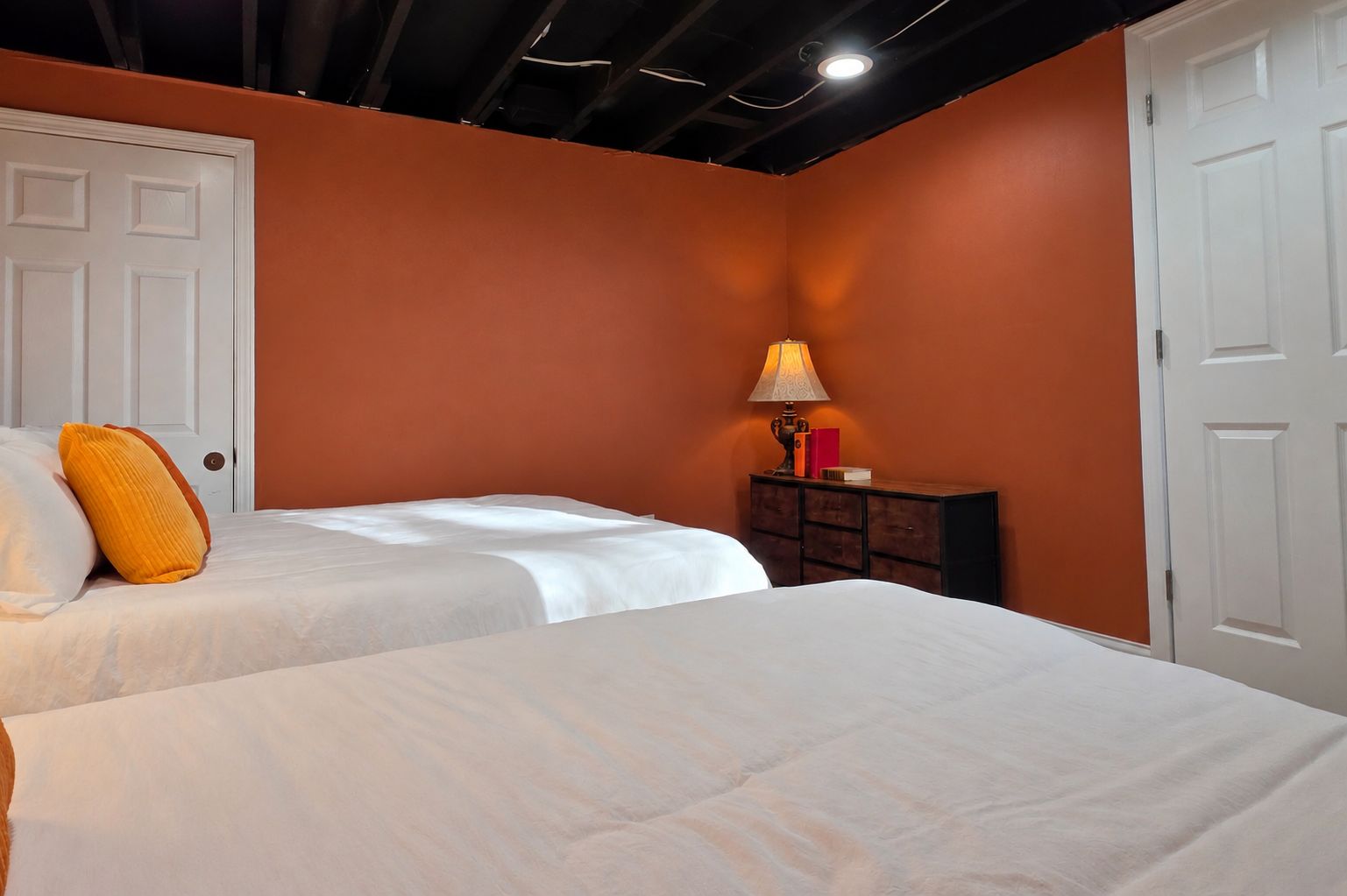 Una camera da letto con due letti, un comodino con una lampada e una porta.