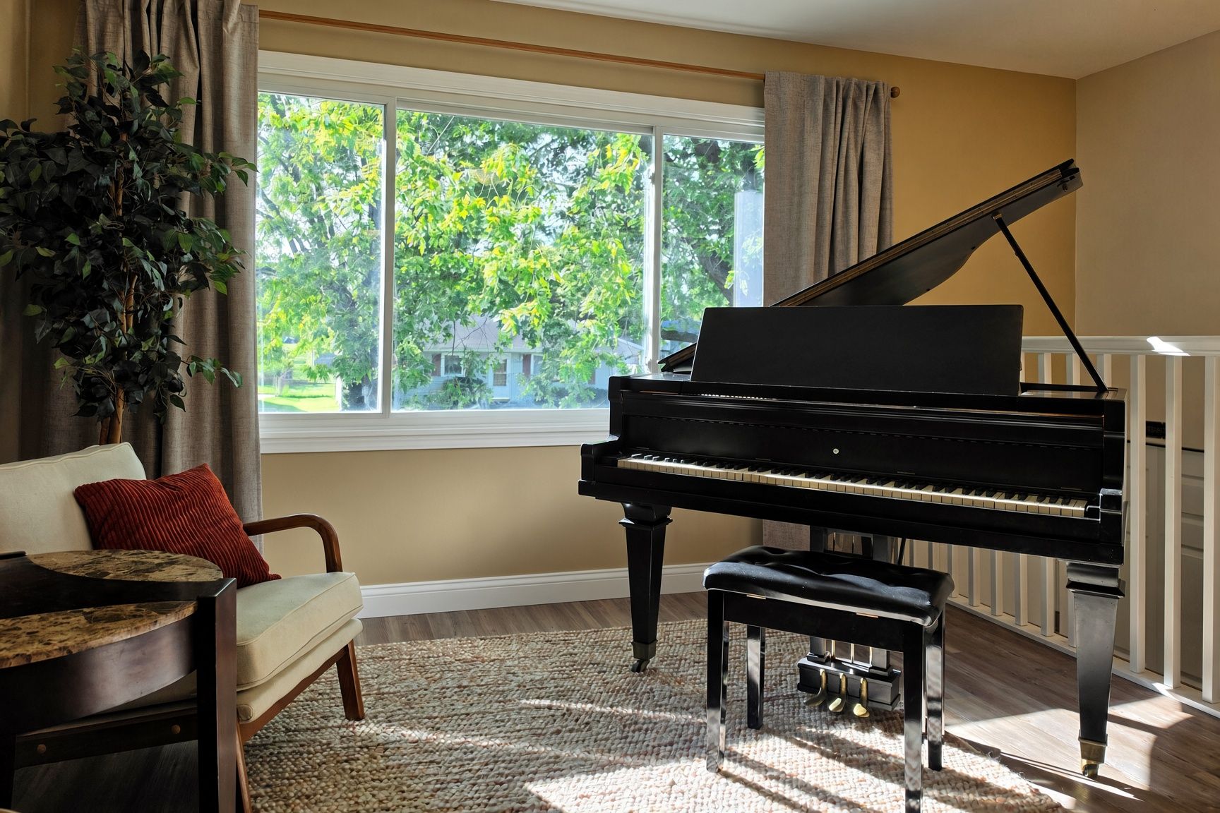 A room with a grand piano, a sofa, a window with curtains, and a plant.