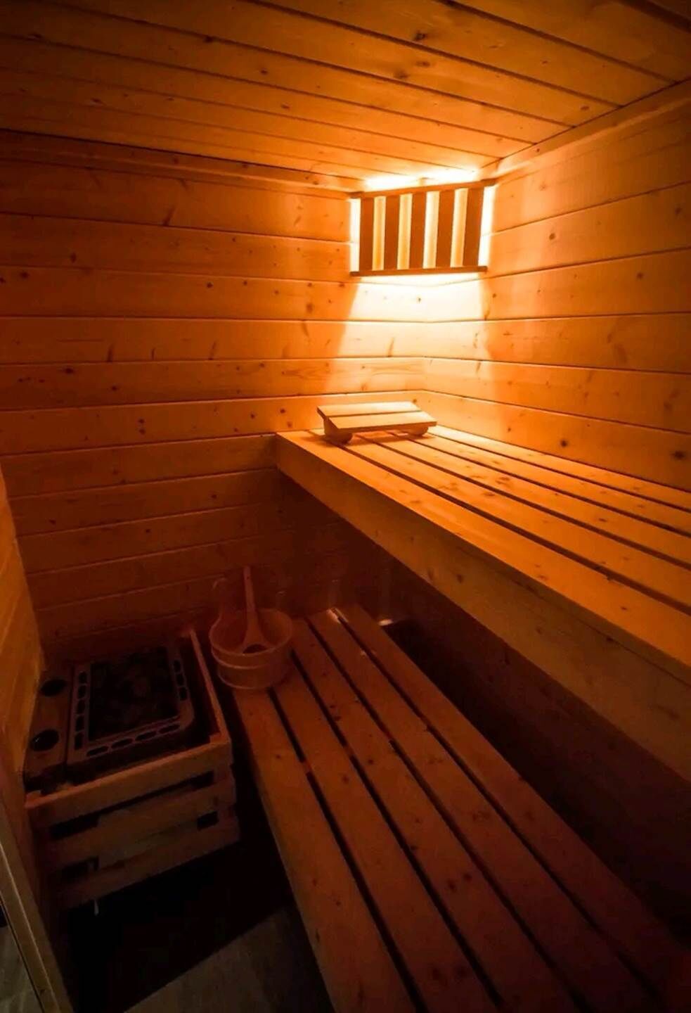A sauna with wooden benches and a bench heater.
